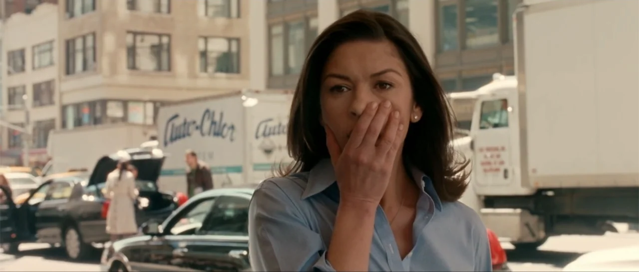 The Rebound (2009) movie still: medium — An urban setting with parked vehicles and commercial buildings in the background. A woman in a blue shirt…