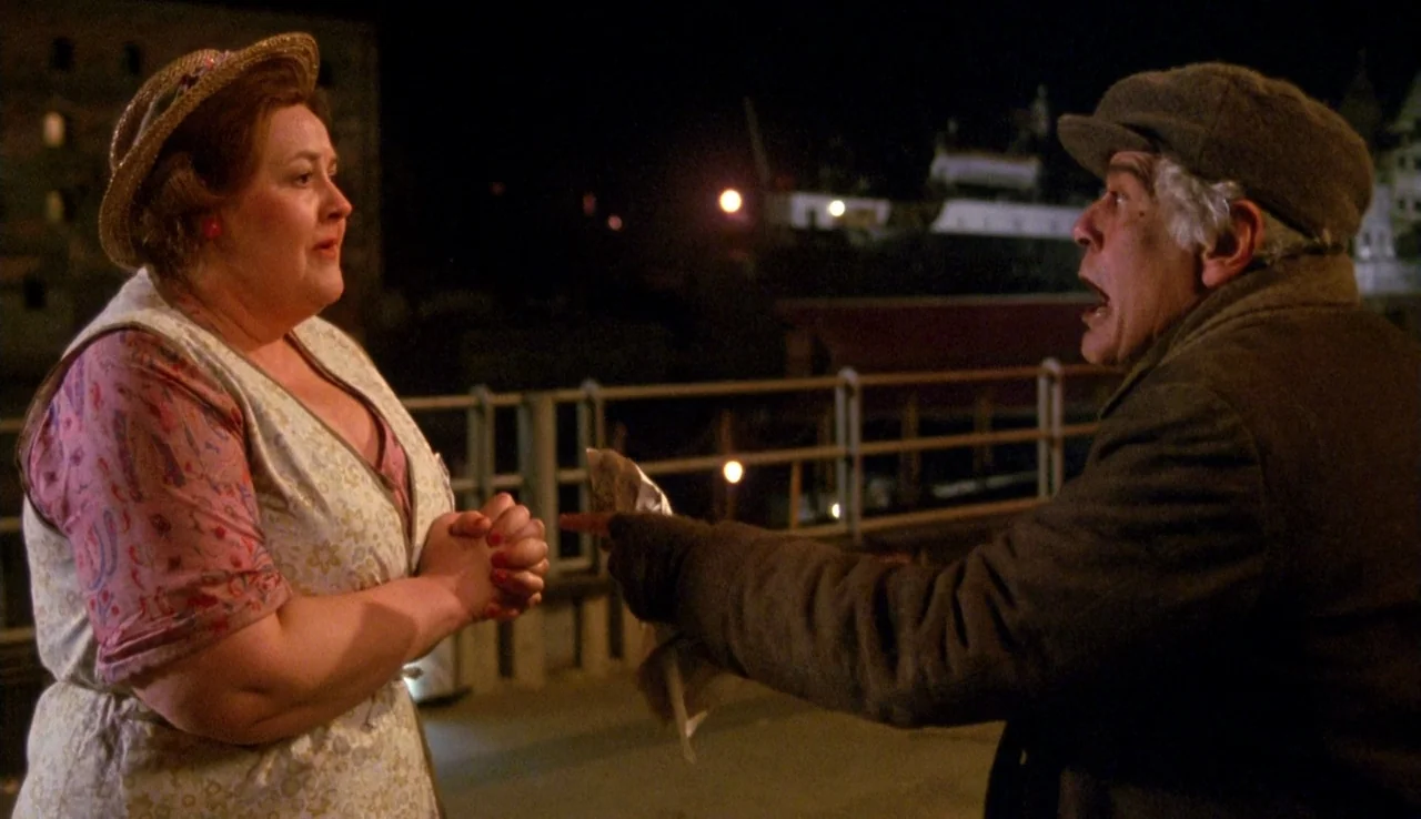 The Rainbow Thief (1990) movie still: medium — An industrial waterfront area at night features metal railings against a dark shipping harbor. A man…