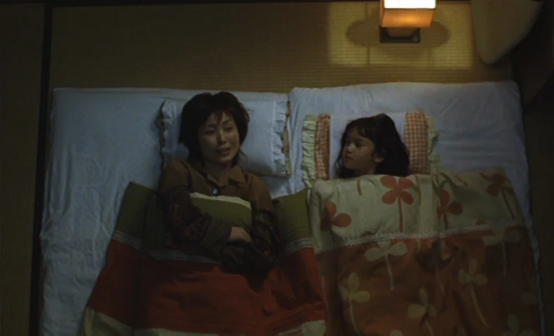 The Taste of Tea (2004) movie still: medium — A Japanese-style room with a straw tatami floor features a futon mattress. An adult woman and a young…