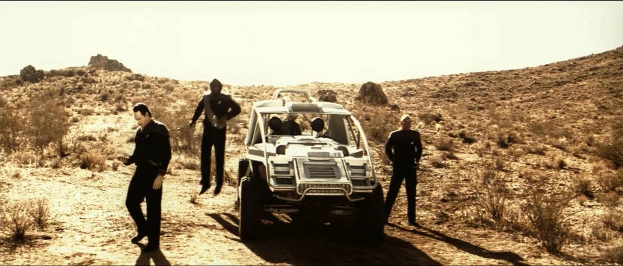Star Trek: Nemesis (2002) movie still: wide — A dry, rocky desert landscape stretches out under a clear, bright sky. Three crew members in dark…