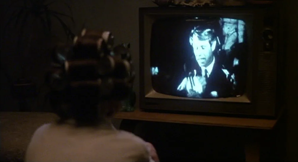 Coming Home (1978) movie still: medium — A dimly lit room focuses on the back of a person with hair rollers. The subject sits before a vintage…