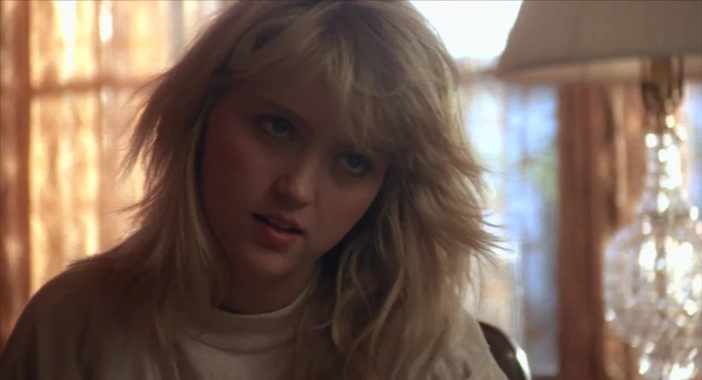 A Nightmare On Elm Street 4: The Dream Master (1988) movie still: closeup — A teenage girl with blonde hair sits in a brightly lit indoor space. She…
