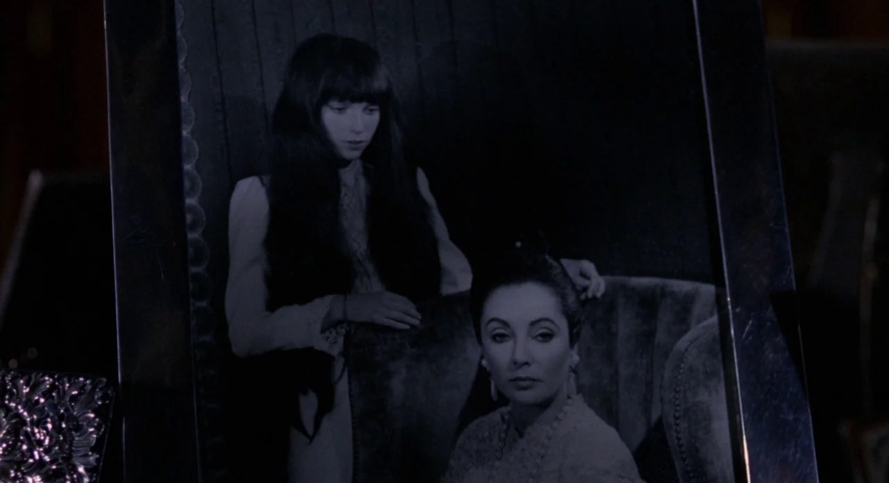 Secret Ceremony (1968) movie still: closeup — A close-up shot of a framed black and white photograph resting on a surface. The photograph depicts…
