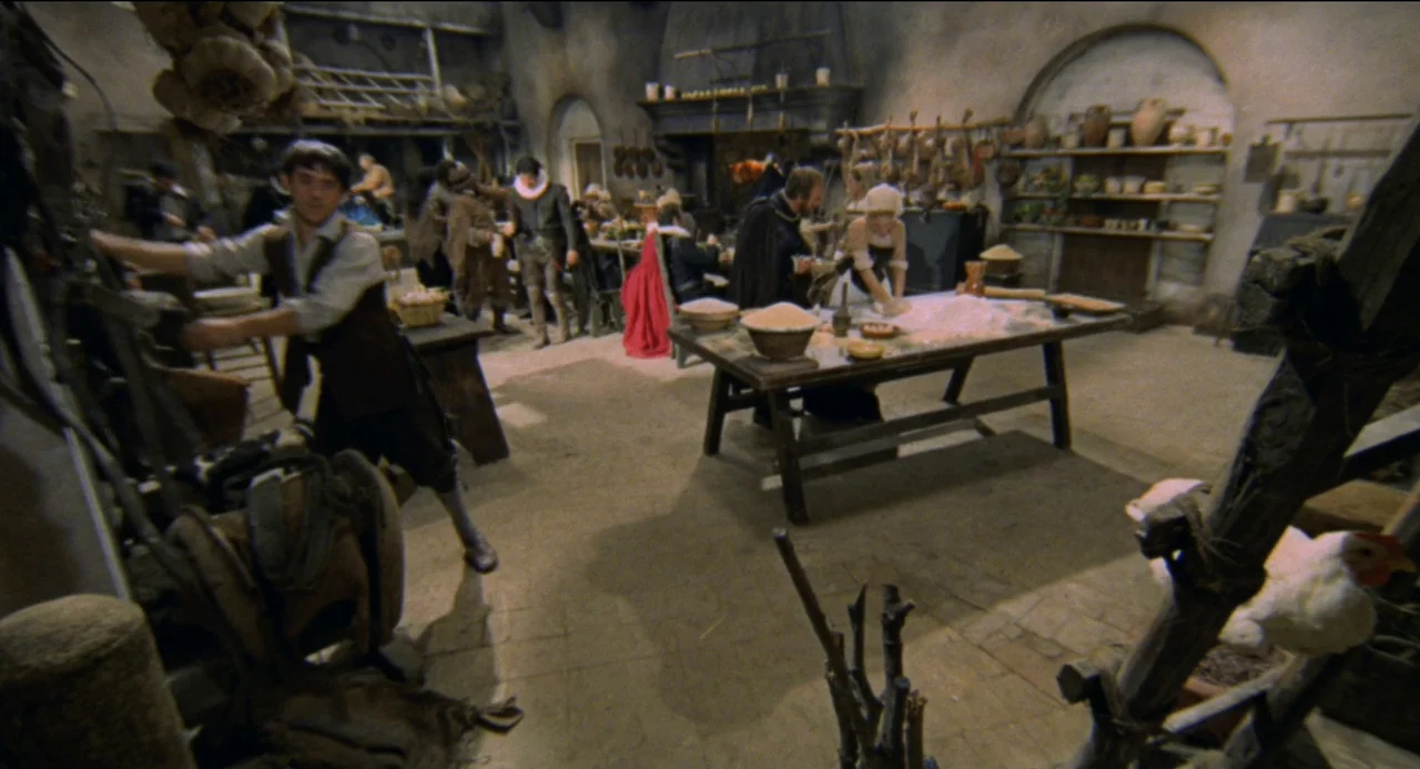 Beatrice Cenci (1969) movie still: wide — A rustic tavern features stone walls and hanging produce with multiple figures present. A man stands near…