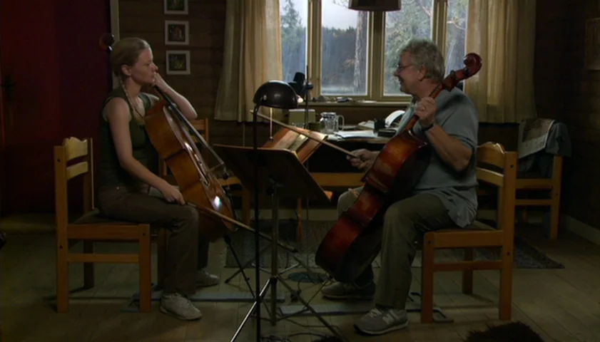 Saraband (2003) movie still: wide — A rustic wooden room contains two musicians practicing their instruments in front of a window. They sit on…