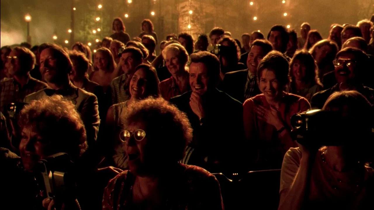 In Dreams (1999) movie still: wide — A dense crowd of people sits in a dark, dimly lit venue. Members of the audience are actively filming the event…