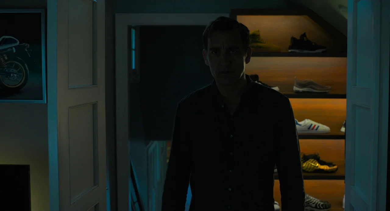 Gemini Man (2019) movie still: medium — A man stands in the doorway of a darkened storage room with illuminated shelves. Rows of athletic sneakers…