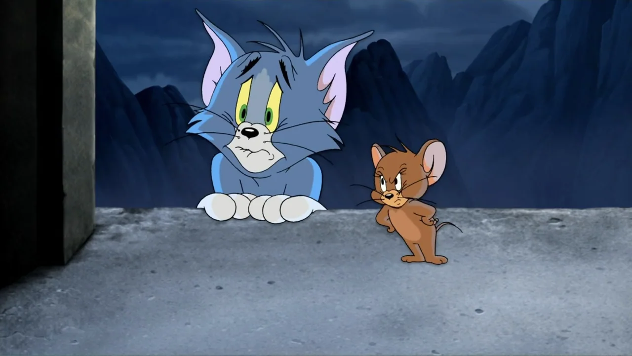 Tom and Jerry & The Wizard of Oz (2011) movie still: medium — A grey concrete ledge overlooks dark, jagged mountains under a night sky. A blue cat…