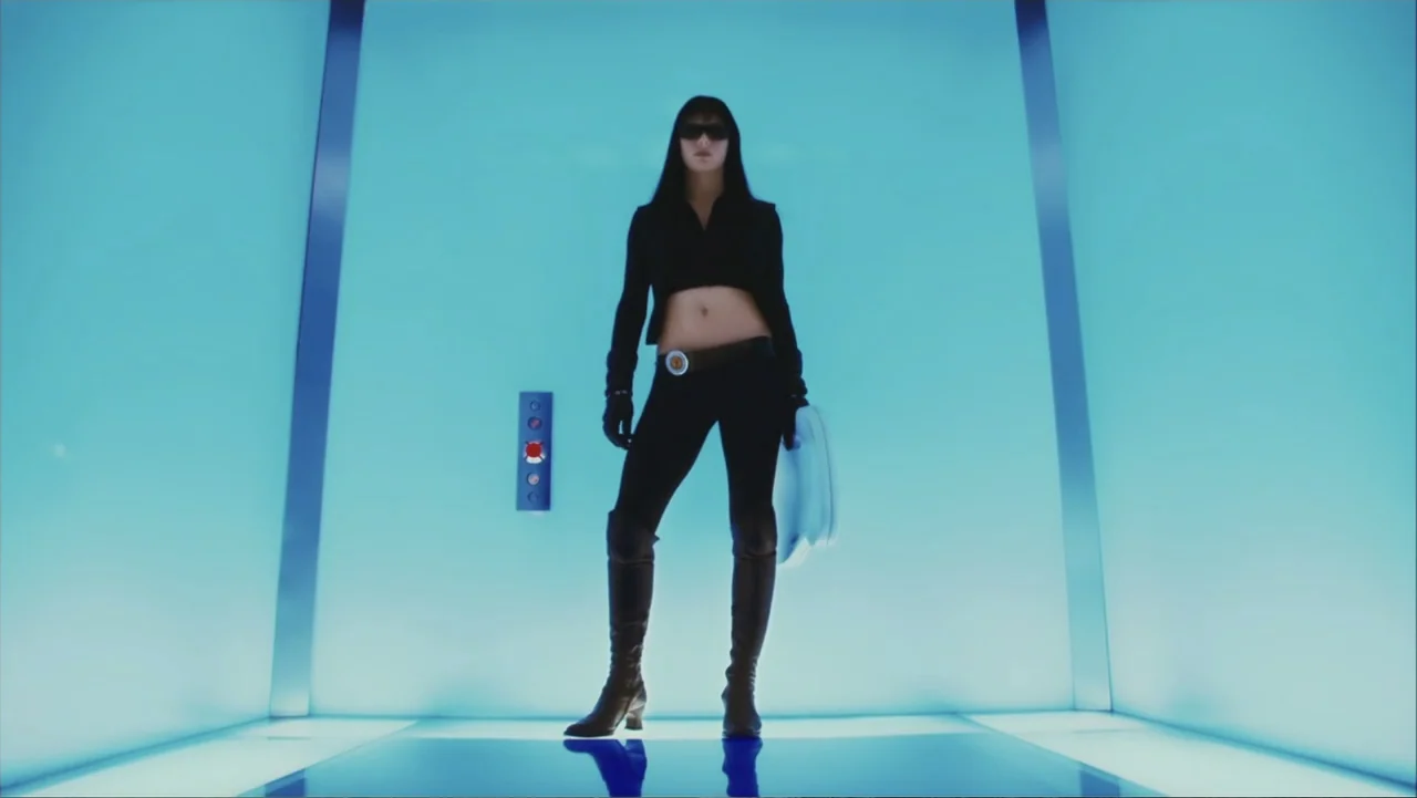 Ultraviolet (2006) movie still: fullbody — A stark, minimalist elevator interior is illuminated by bright blue panels on all sides. A woman stands…