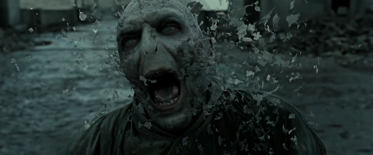 Harry Potter & The Deathly Hallows Part 2 (2011) movie still: closeup — A ruined outdoor space with debris scattered on the ground. A bald man is…
