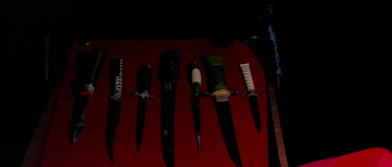 The Bird With The Crystal Plumage (1970) movie still: closeup — Seven distinct knives are lined up symmetrically on a red velvet display board. The…