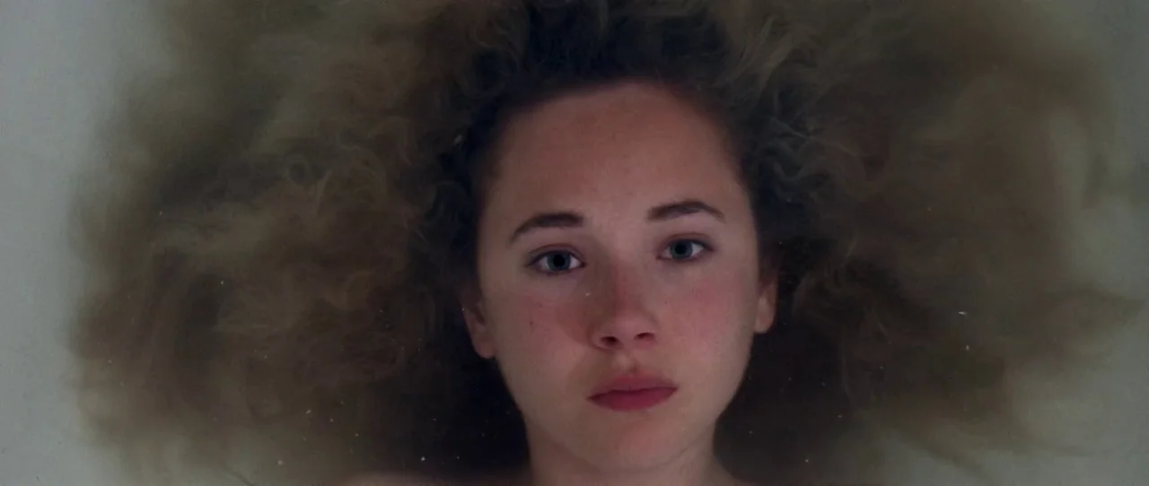 Little Birds (2011) movie still: closeup — A woman lies submerged in water inside a bathtub with her hair spread out. The camera is positioned…