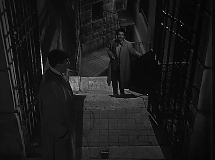 Variety Lights (1950) movie still: fullbody — A narrow stone staircase between high walls in a dark urban environment at night. Two men in long…