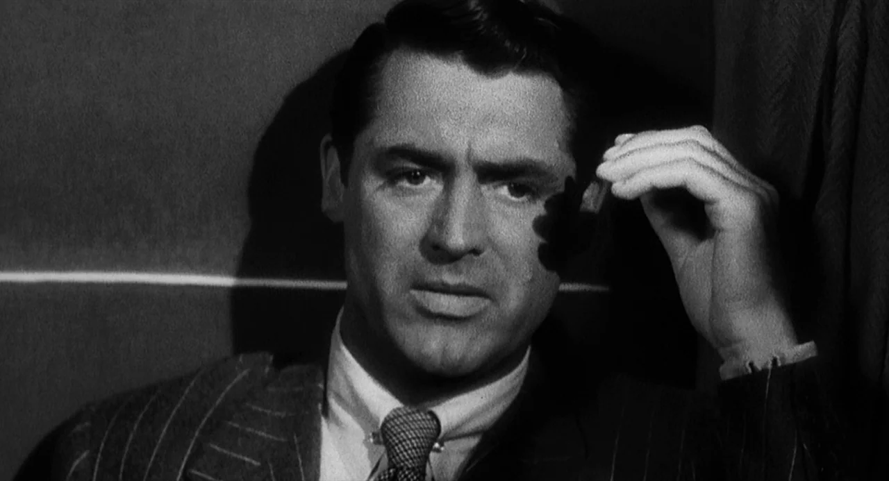 Dead Men Don’t Wear Plaid (1982) movie still: closeup — A dimly lit train compartment features plain walls and dark vertical paneling. A man in a…
