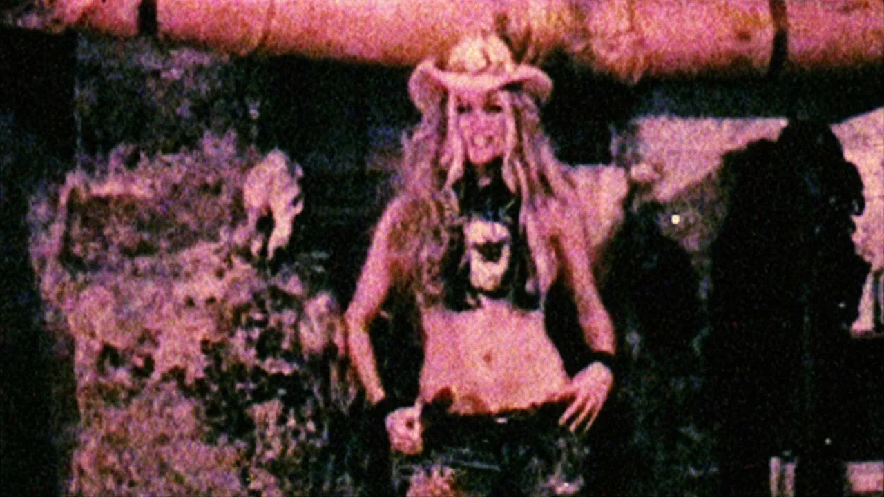 House of 1000 Corpses (2003) movie still: medium — A dark space with indistinct textured walls lit by intense pink stage lights. A young woman…