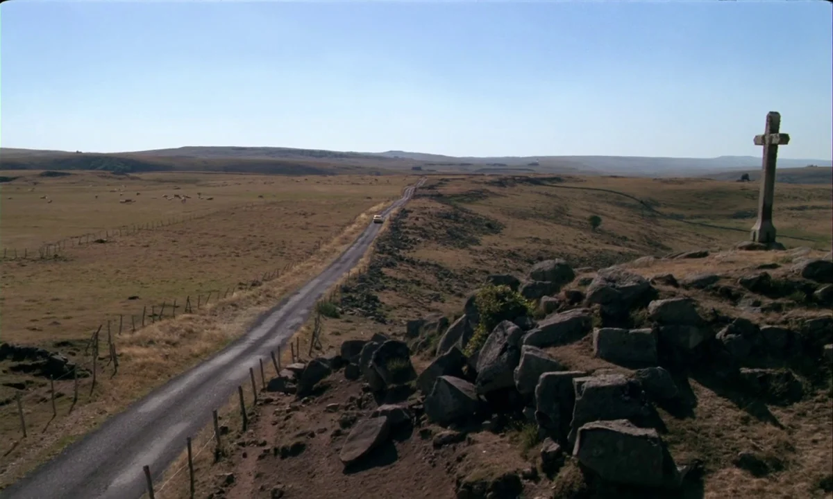 Betty Blue (1986) movie still: establishing — An expansive, dry moorland landscape features a lone road stretching toward the distant horizon. A…