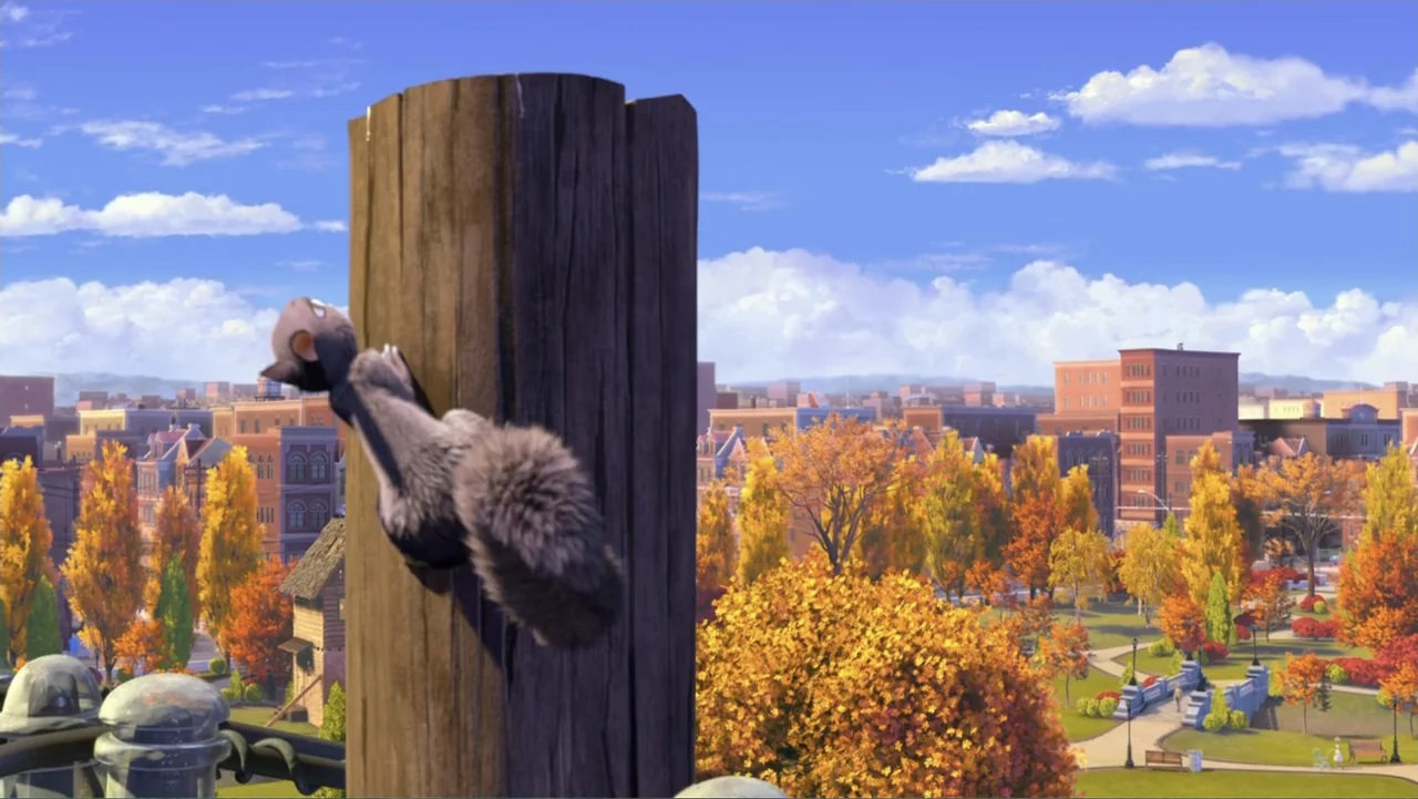 The Nut Job (2014) movie still: medium — A cartoon squirrel clings to a vertical wooden post in a public park. Autumn foliage and residential…