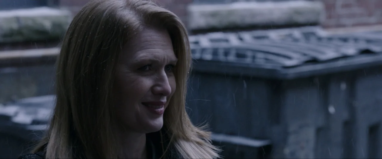The Lie (2018) movie still: closeup — An exterior urban alleyway features a large dark dumpster in the background during rain. A woman with blonde…