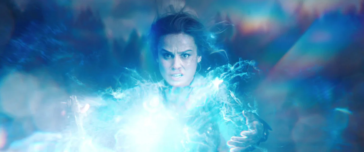 Captain Marvel (2019) movie still: closeup — A woman stands in a blurred, undefined environment saturated with bright blue light effects. She…