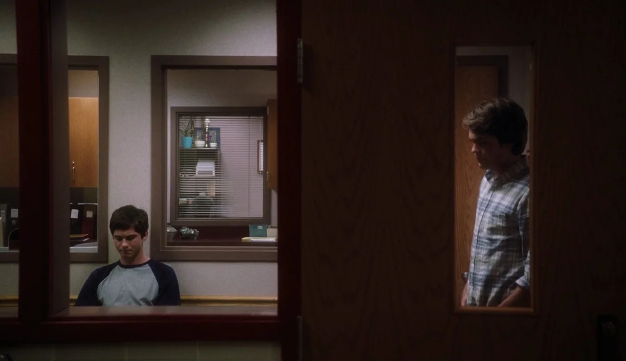The Perks of Being A Wallflower (2012) movie still: medium — A school interior shows two men separated by a doorway. The student sits at a desk…