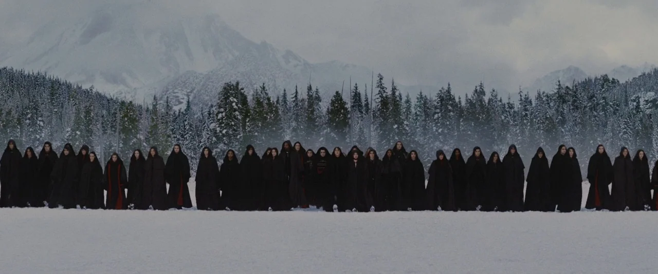 The Twilight Saga: Breaking Dawn – Part 2 (2012) movie still: wide — A long line of figures in black hooded robes stands on a snowy plain. Dense…
