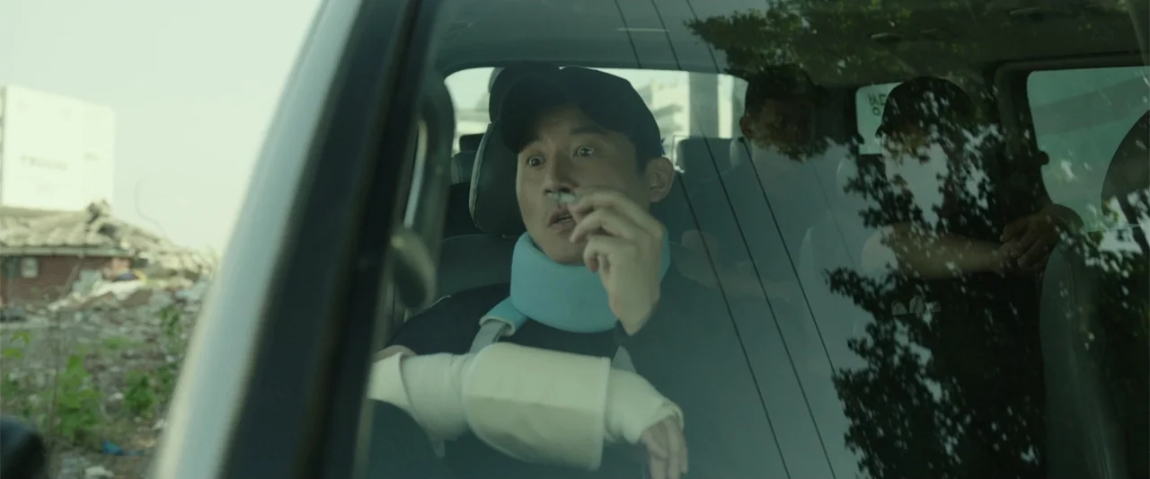 Along with the Gods: The Last 49 Days (2018) movie still: medium — A man sits in the passenger seat of a car looking through the windshield. He…