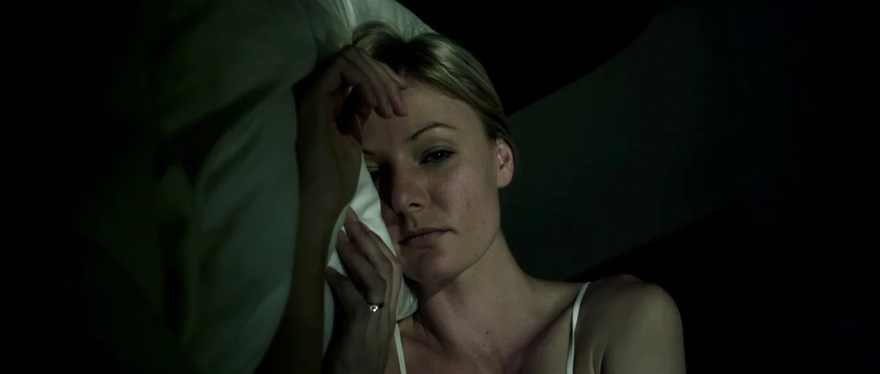 Universal Soldier: Day of Reckoning (2012) movie still: closeup — A dark space features a person lying against a pillow in low lighting. A woman…