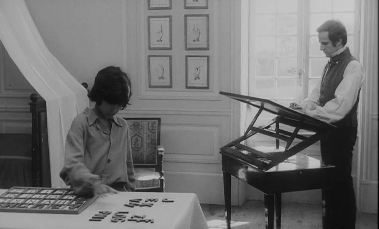 The Wild Child (1970) movie still: medium — A light-filled study features framed anatomical prints on the wall and a desk. An adult man writes at a…