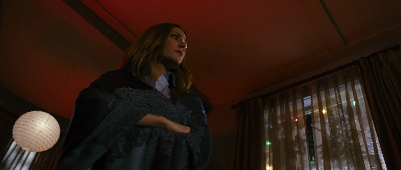 Black Christmas (2006) movie still: medium — A dimly lit room features a paper lantern and a window with sheer curtains. A woman stands in the…