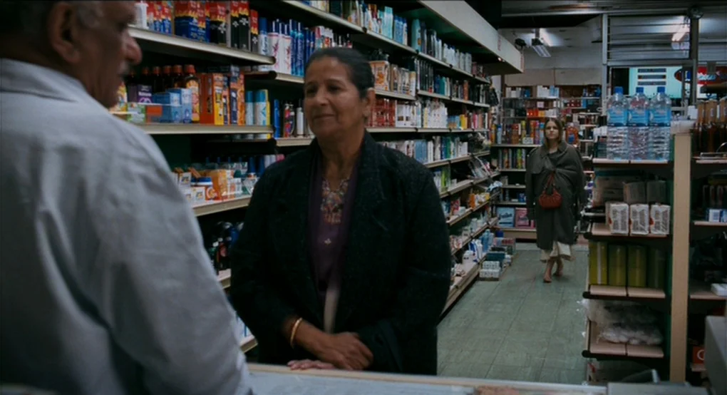 Eastern Promises (2007) movie still: medium — A small retail shop aisle is lined with metal shelving stocked with packaged goods. An elderly man in…