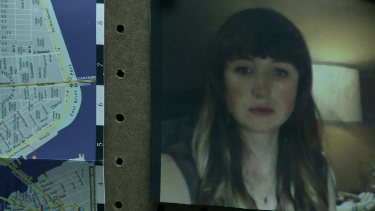 The Heart Machine (2014) movie still: closeup — A printed photograph of a young woman is pinned to a dark cork board. A folded street map of…