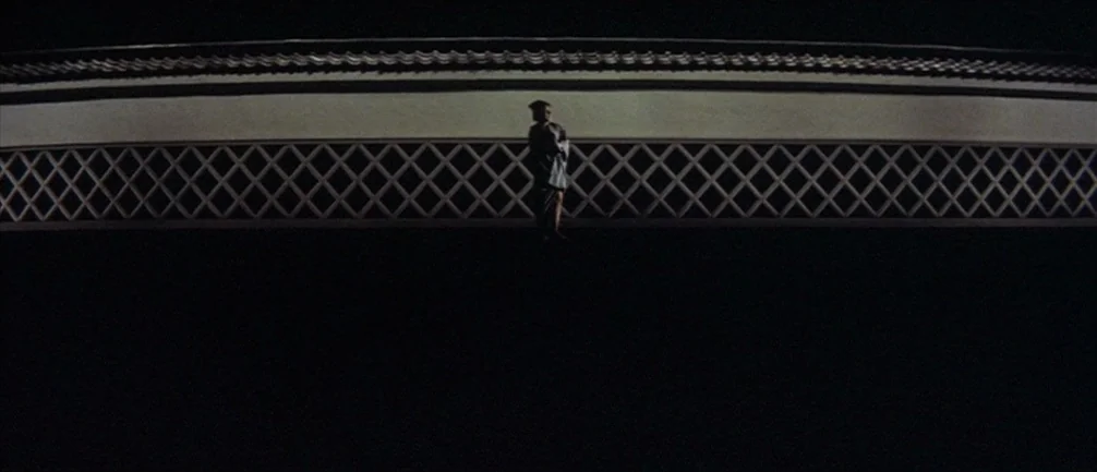 An Actor’s Revenge (1963) movie still: wide — A long, flat fortress wall features a distinctive lattice wooden frame pattern at the top. A lone…
