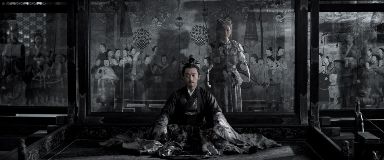 Shadow (2018) movie still: medium — An ornate interior features a large folding screen decorated with intricate line art figures. A man dressed in…