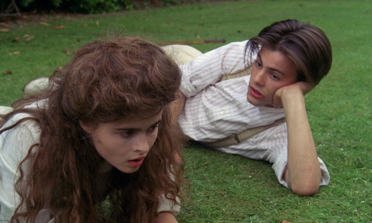 A Room With A View (1985) movie still: medium — A green manicured lawn in an open outdoor setting. A young woman and a young man lie on the grass…
