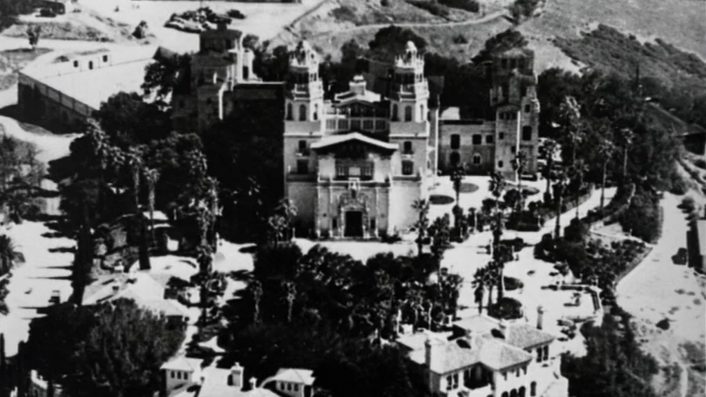 Patty Hearst (1988) movie still: establishing — An aerial view of a large Mediterranean-style estate complex surrounded by dense trees. Winding…
