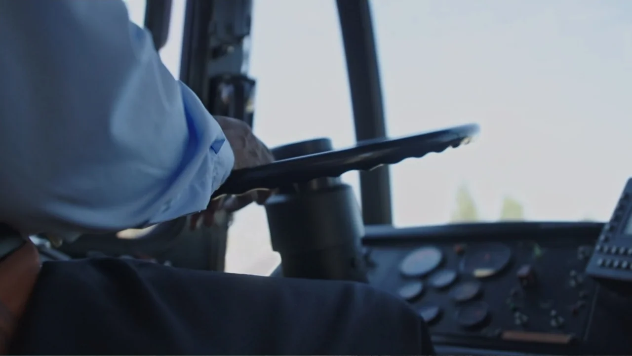 Murders at the Burger Joint (2022) movie still: medium — The interior of a bus cockpit features a large steering wheel and dashboard gauges. A…