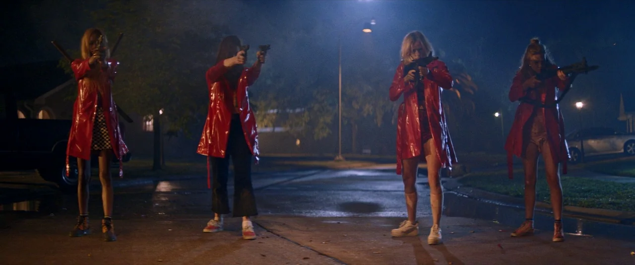 Assassination Nation (2018) movie still: fullbody — A quiet suburban street at night is illuminated by tall flickering streetlamps. Four women…