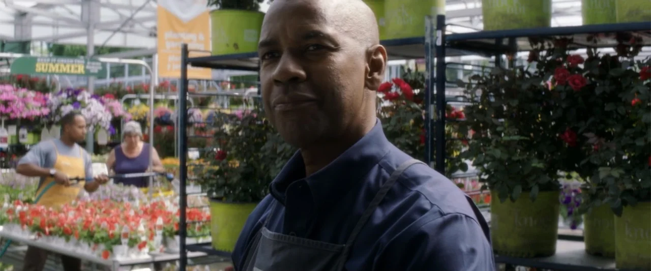 The Equalizer (2014) movie still: medium — A well-stocked indoor nursery displays rows of potted plants on metal shelving units. A man wearing an…