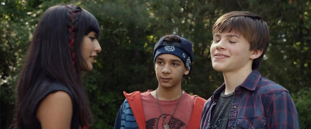 Max (2002) movie still: medium — Three teenagers stand in a wooded area with dense green foliage behind them. The group consists of one girl and two…