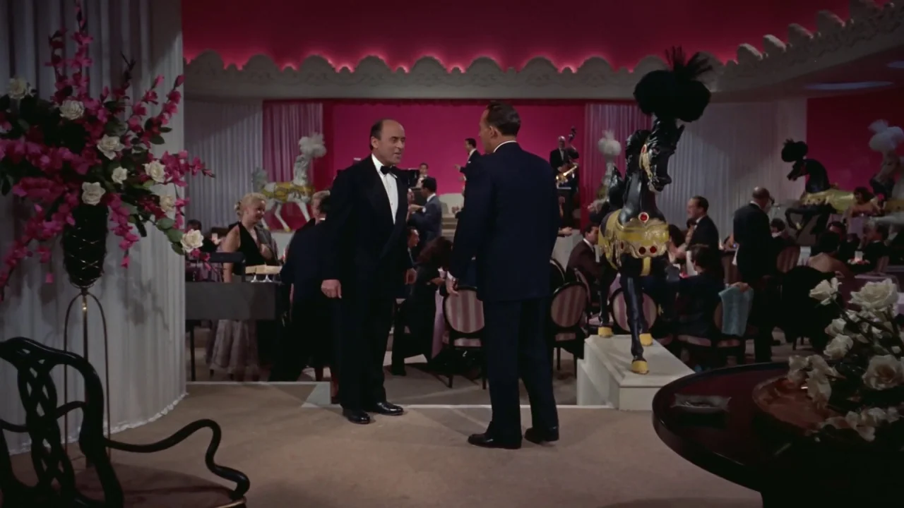 White Christmas (1954) movie still: fullbody — A high-end nightclub features pink walls, carousel horses, and guests seated at tables. Two men in…