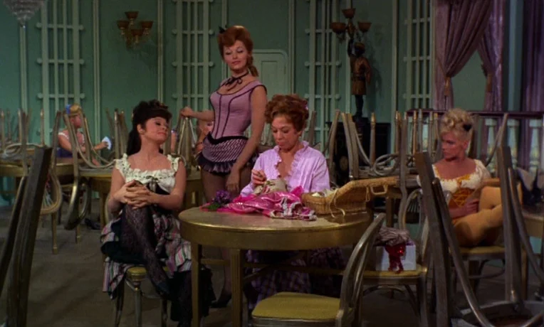 Frankie and Johnny (1966) movie still: medium — A vintage cabaret room with green paneling and numerous chairs stacked on tables. Four women in…