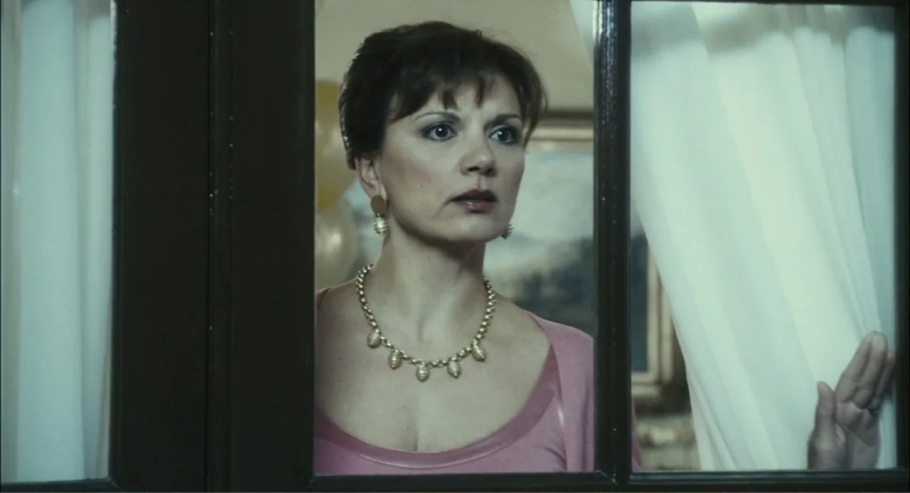 El hijo del diablo (1966) movie still: medium — A woman stands behind a framed glass door with white curtains on either side. She looks outward with…