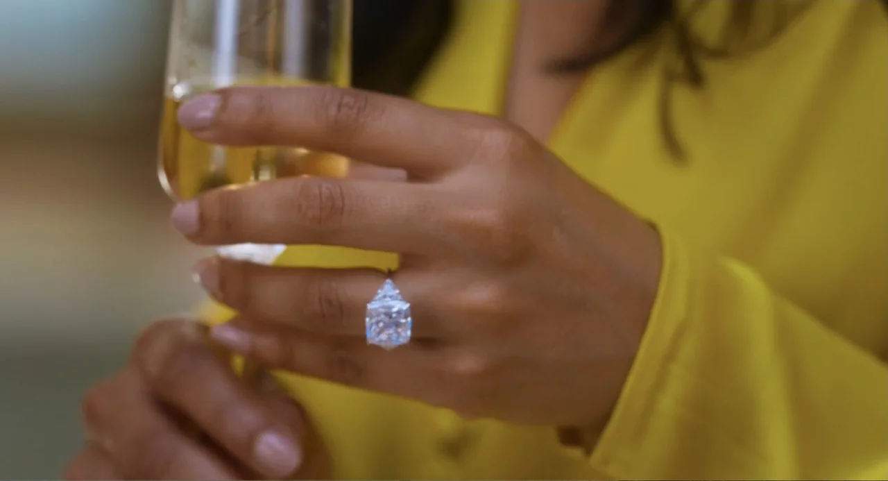 Tom & Jerry (2021) movie still: closeup — A close view of a person's hand wearing a large diamond engagement ring. The person wears a yellow…