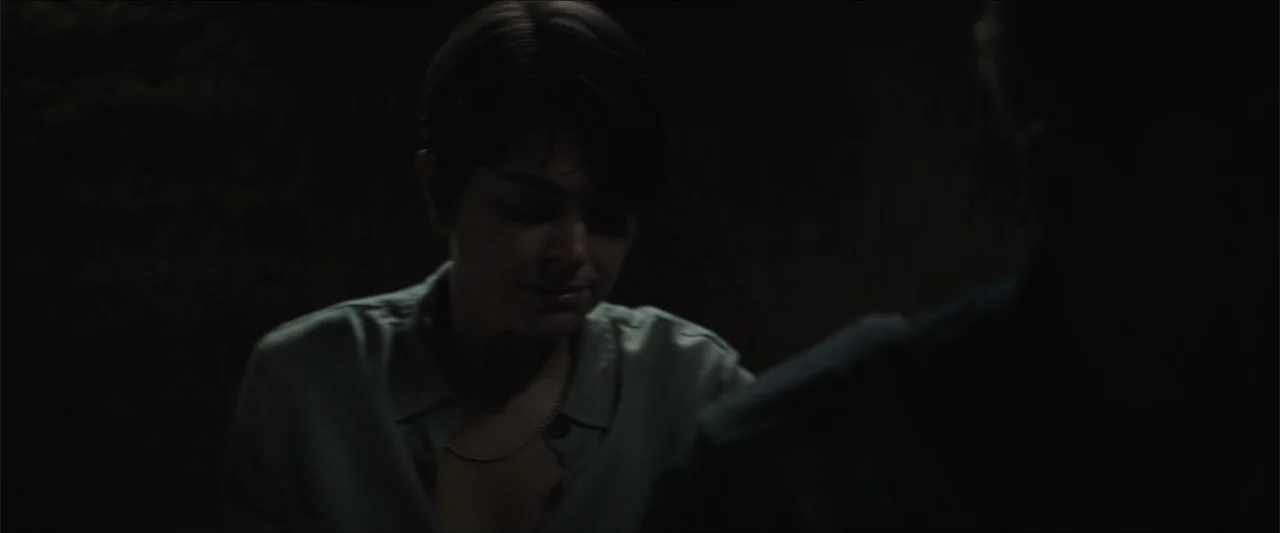 Redemption Day (2021) movie still: medium — A dimly lit interior space with dark walls and minimal environmental detail. A young woman with short…