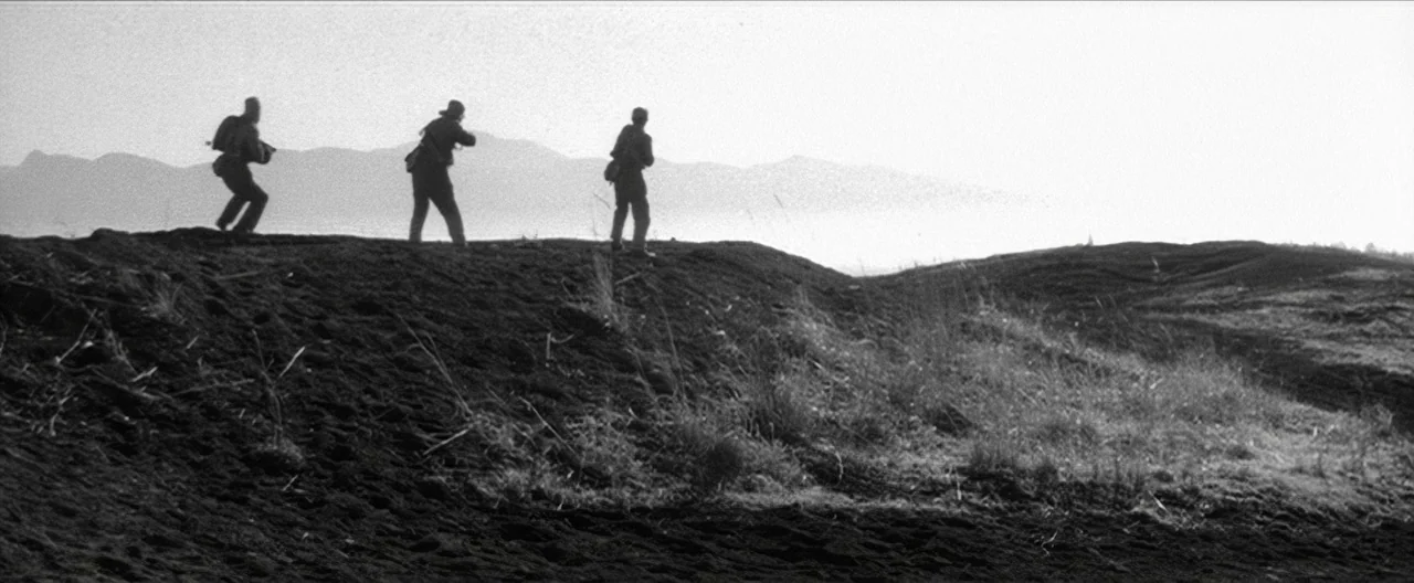 Story of a Prostitute (1965) movie still: wide — Three figures walk across a barren dark ridge beneath an expansive bright sky. Distant hazy…