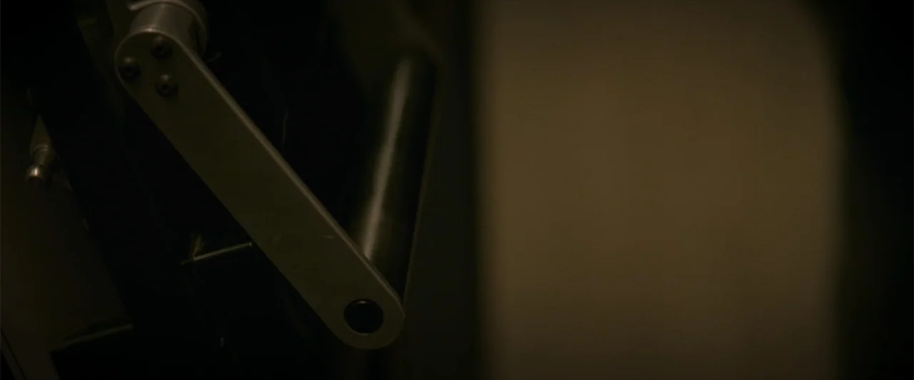 Treblinka's Last Witness (2012) movie still: closeup — An industrial metal lever or handle is positioned against a dark, featureless wall. The…
