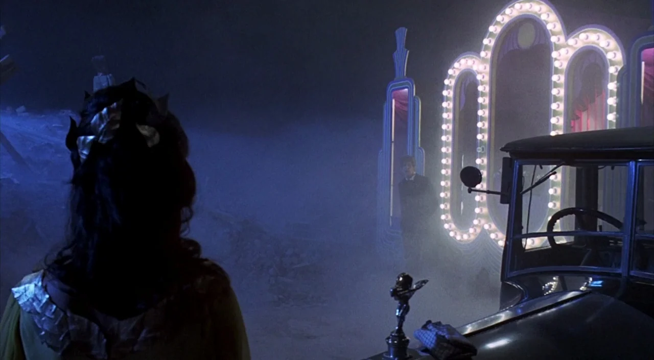 Dr. Phibes Rises Again (1972) movie still: medium — A dark, misty outdoor fairground set at night with debris scattered on the ground. A woman in…