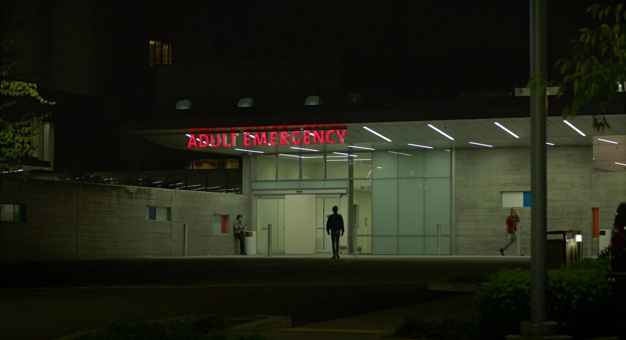 Lean on Pete (2017) movie still: wide — A modern building exterior features concrete walls and a large glass-fronted entrance area. People are…