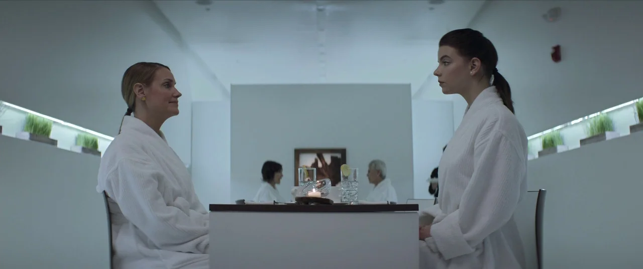 Thoroughbreds (2017) movie still: medium — A stark, minimalist white dining area features recessed wall lighting and artificial grass planters. Two…