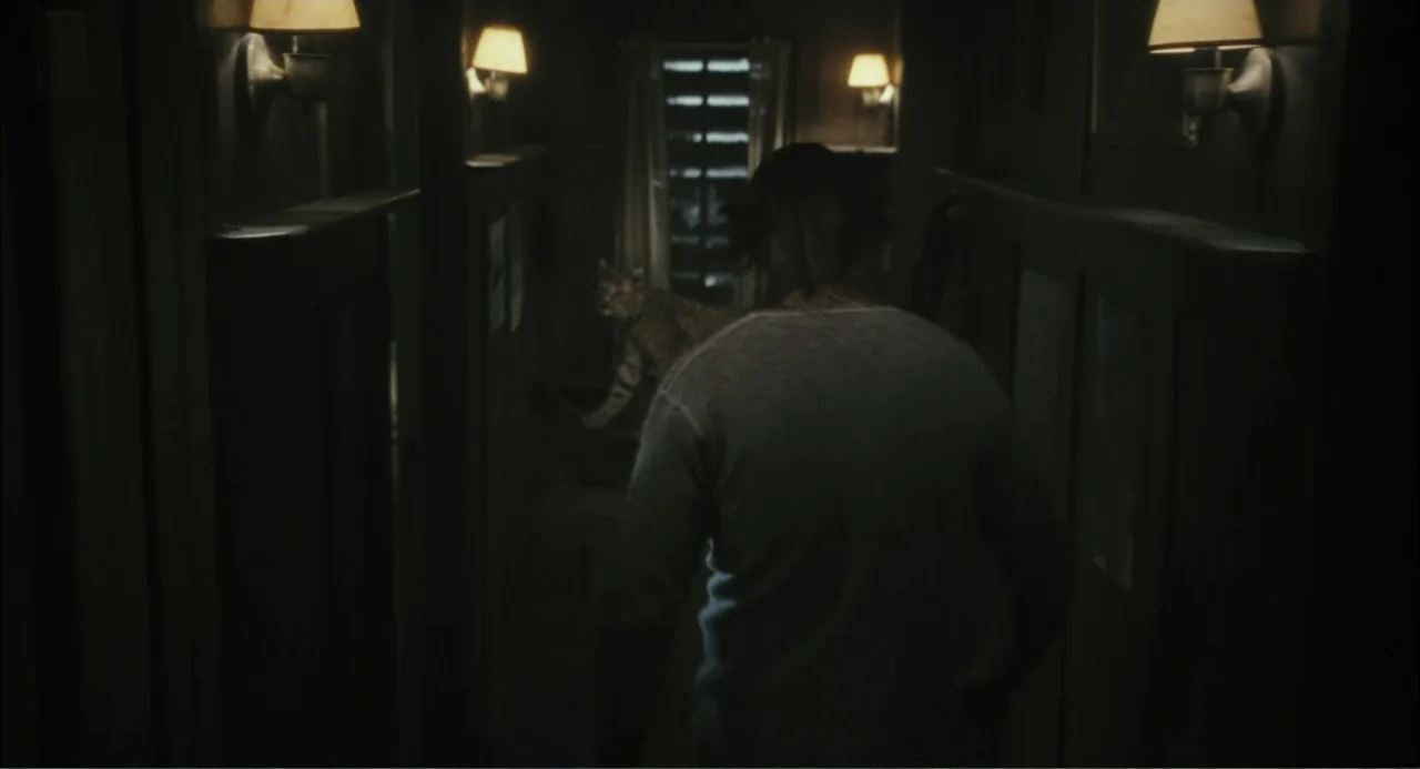 El hijo del diablo (1966) movie still: medium — A dimly lit narrow residential hallway features wooden wall panels and several wall lamps. A person…